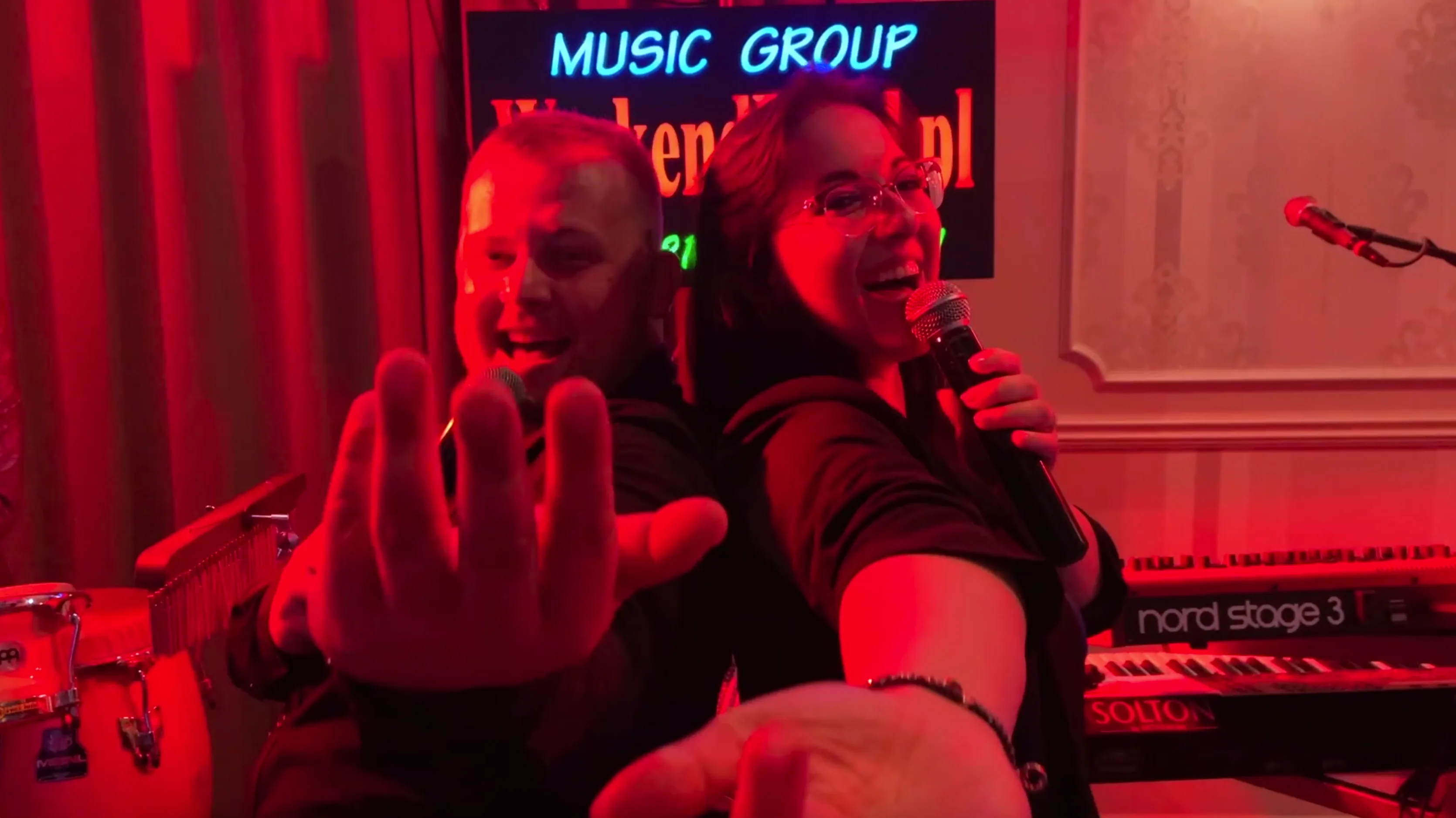 Wokaliści WeekendBand śpiewają razem na scenie w czerwonym świetle.
